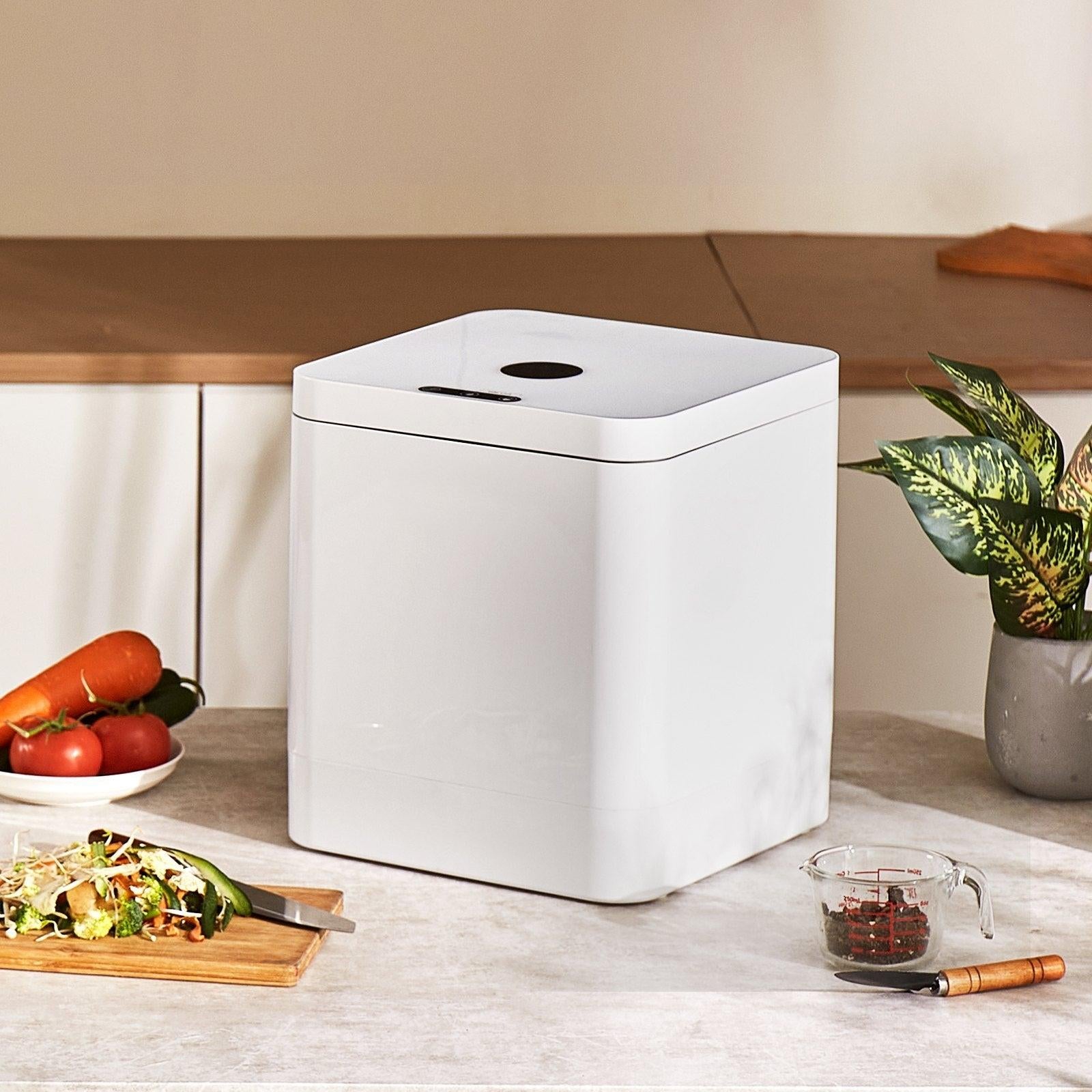 Coocosh Kitchen Compost Bin made from durable plastic, sleek white design, dimensions approx. 12x12x15 inches, displayed on a countertop surrounded by fresh vegetables and a salad, emphasizing eco-friendly waste management.