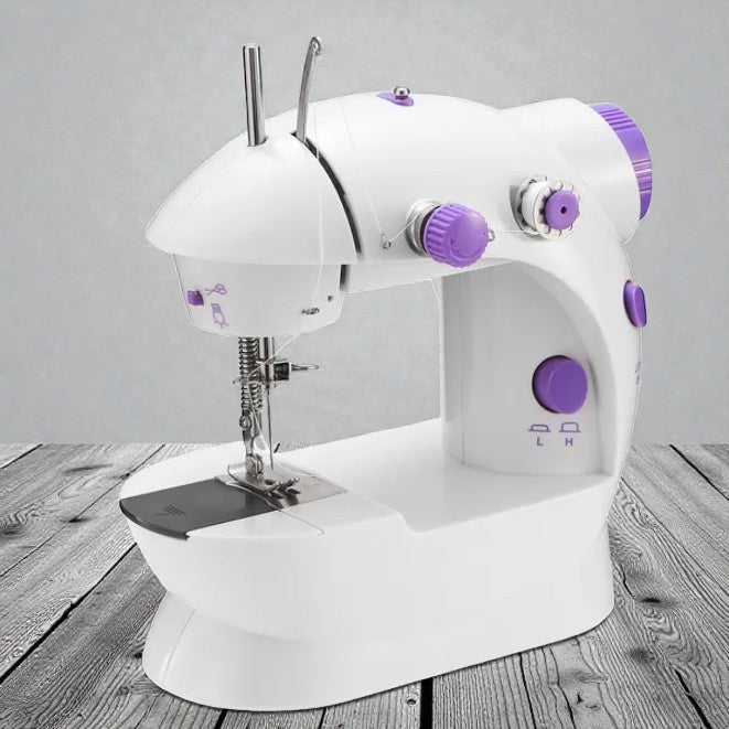 Coocosh Mini Sewing Machine with Dual Speed, crafted from durable white plastic with purple accents, offering compact dimensions for easy portability and home sewing projects. A close-up view on a wood surface.