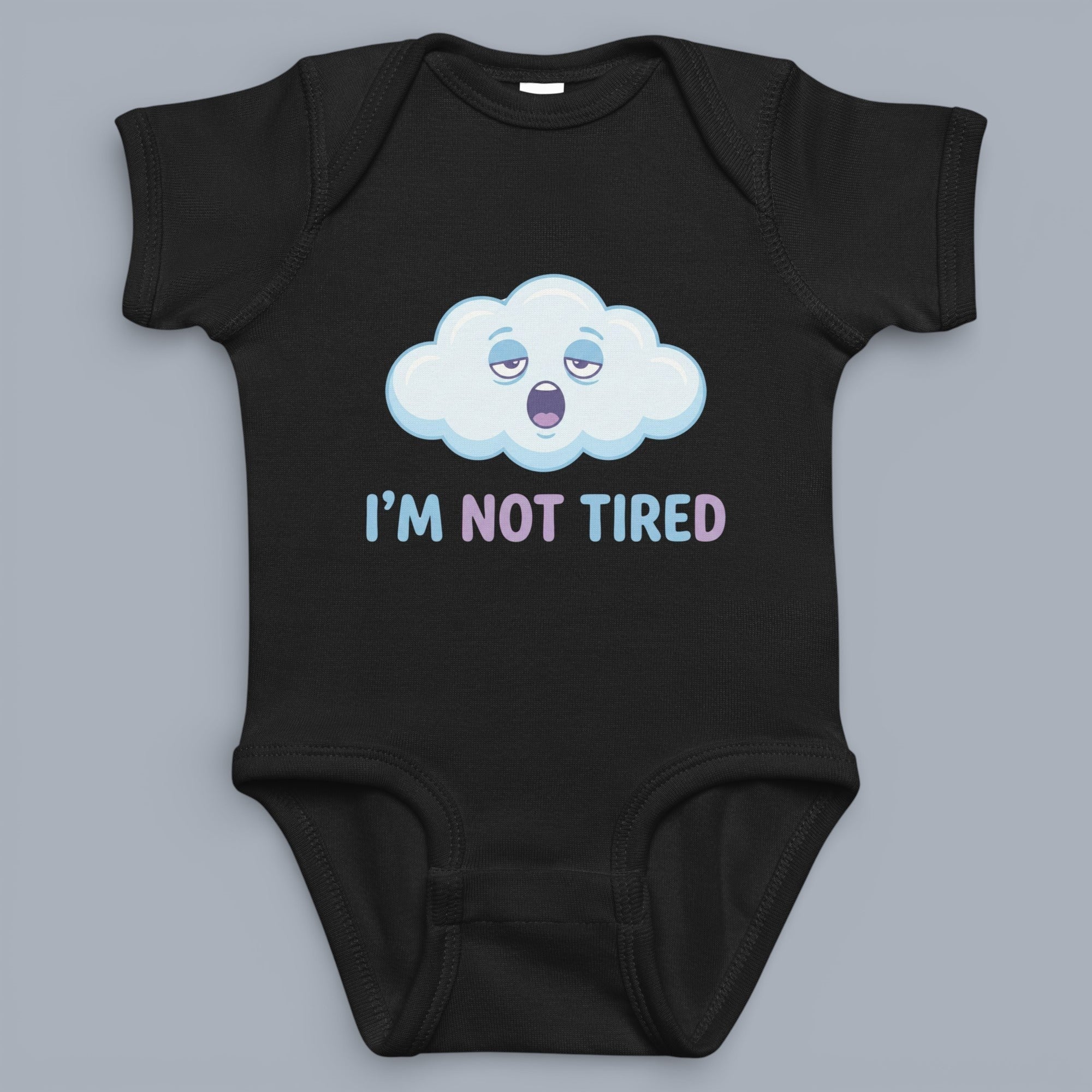 Coocosh Onesie featuring a funny cartoon cloud with sleepy eyes and the text 'I'm Not Tired' in a light blue and light purple, made of soft cotton, in black, displayed flat-lay. Perfect for babies.