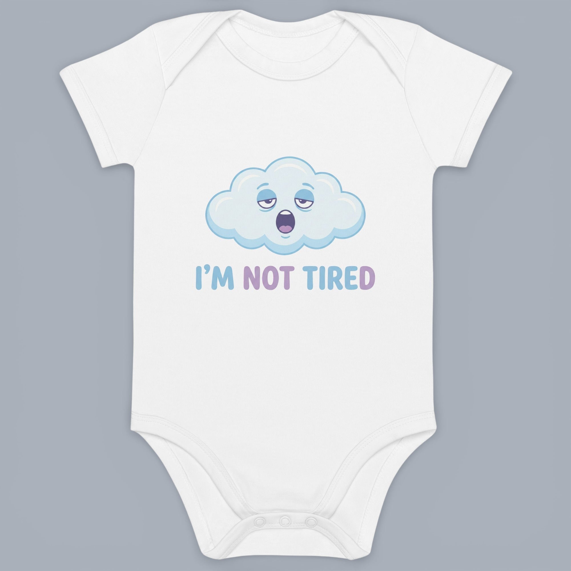 Coocosh Baby Onesie features a funny graphic of a tired cloud with the words "I'M NOT TIRED" printed underneath in a light blue and purple font, white, perfect for everyday wear. It's adorable.