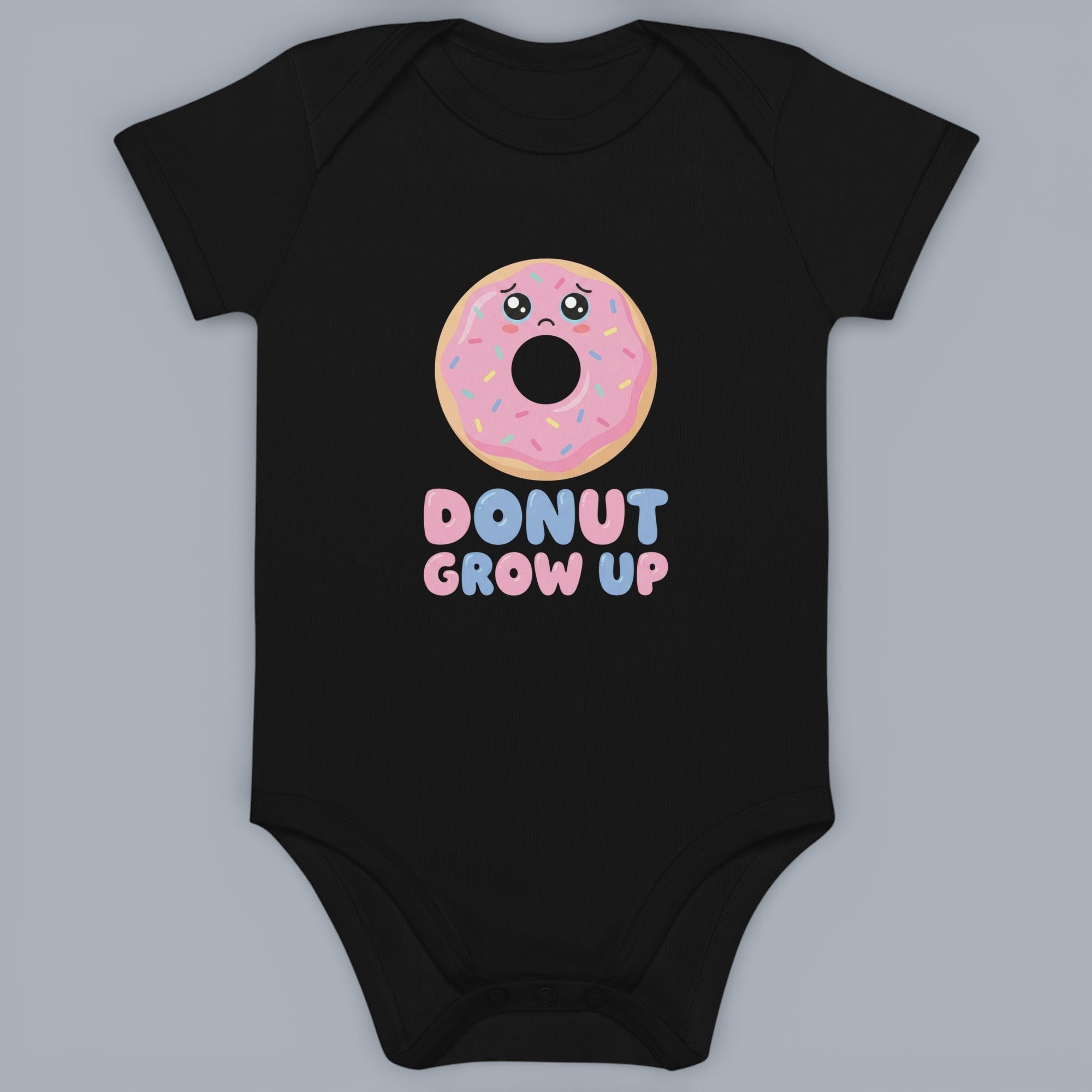 Coocosh black baby onesie with short sleeves. Features a sad cartoon donut with pink frosting and the words "Donut Grow Up" in a cute, playful font. Perfect for baby clothing, and gifts. A fun, stylish piece for your little one's wardrobe.