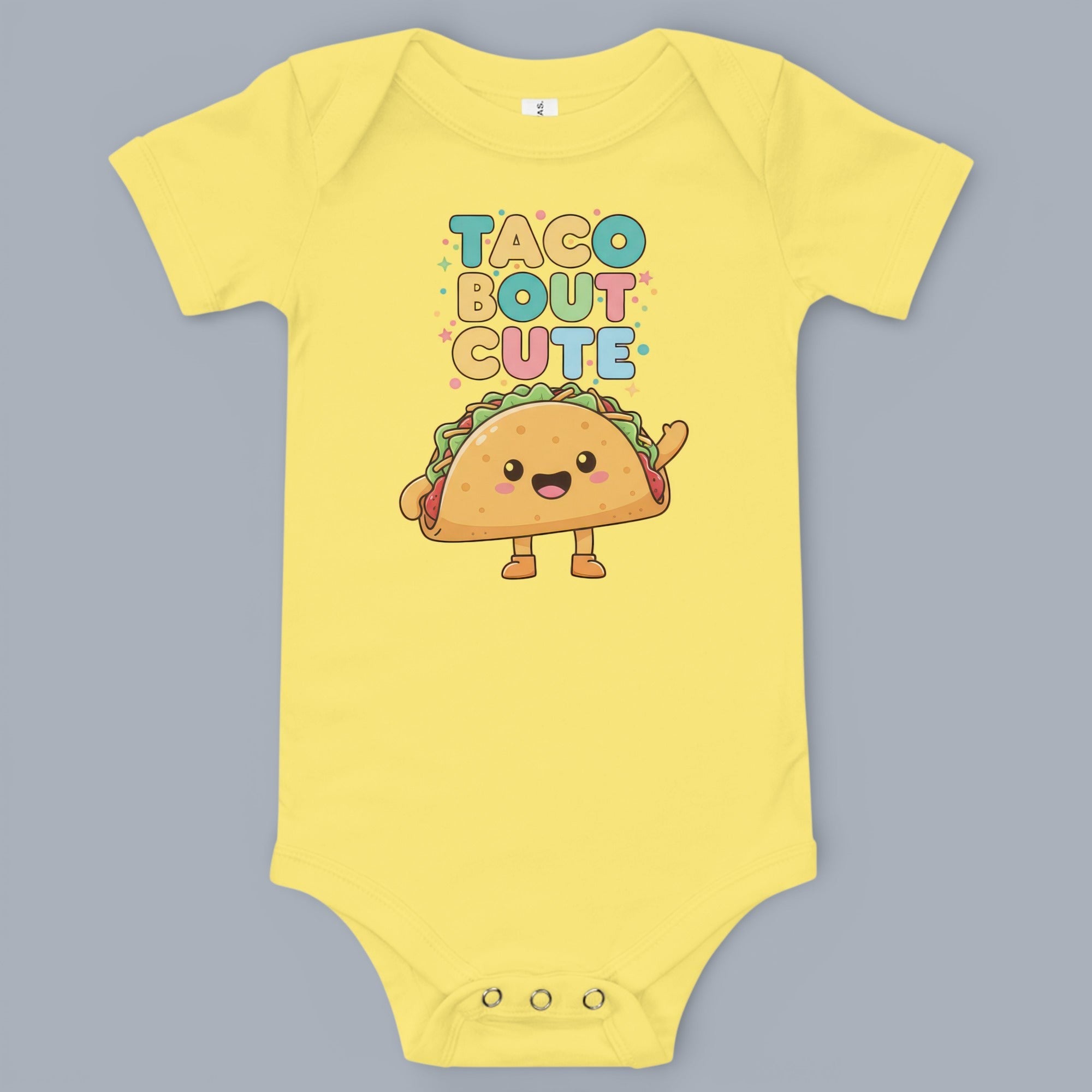 Coocosh Baby Onesie features a playful "Taco Bout Cute" graphic design on a vibrant yellow fabric. Perfect for a fun and comfortable look. A sweet statement piece.