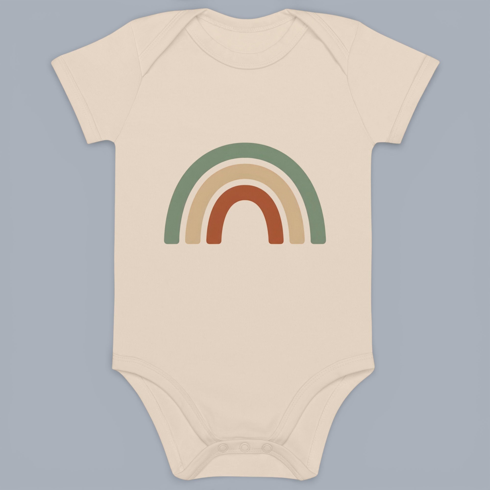 Coocosh baby onesie with a short sleeve design. Features a cute, three-layer rainbow graphic in muted green, beige, and rust colors on a soft, cream-colored cotton. A modern essential.