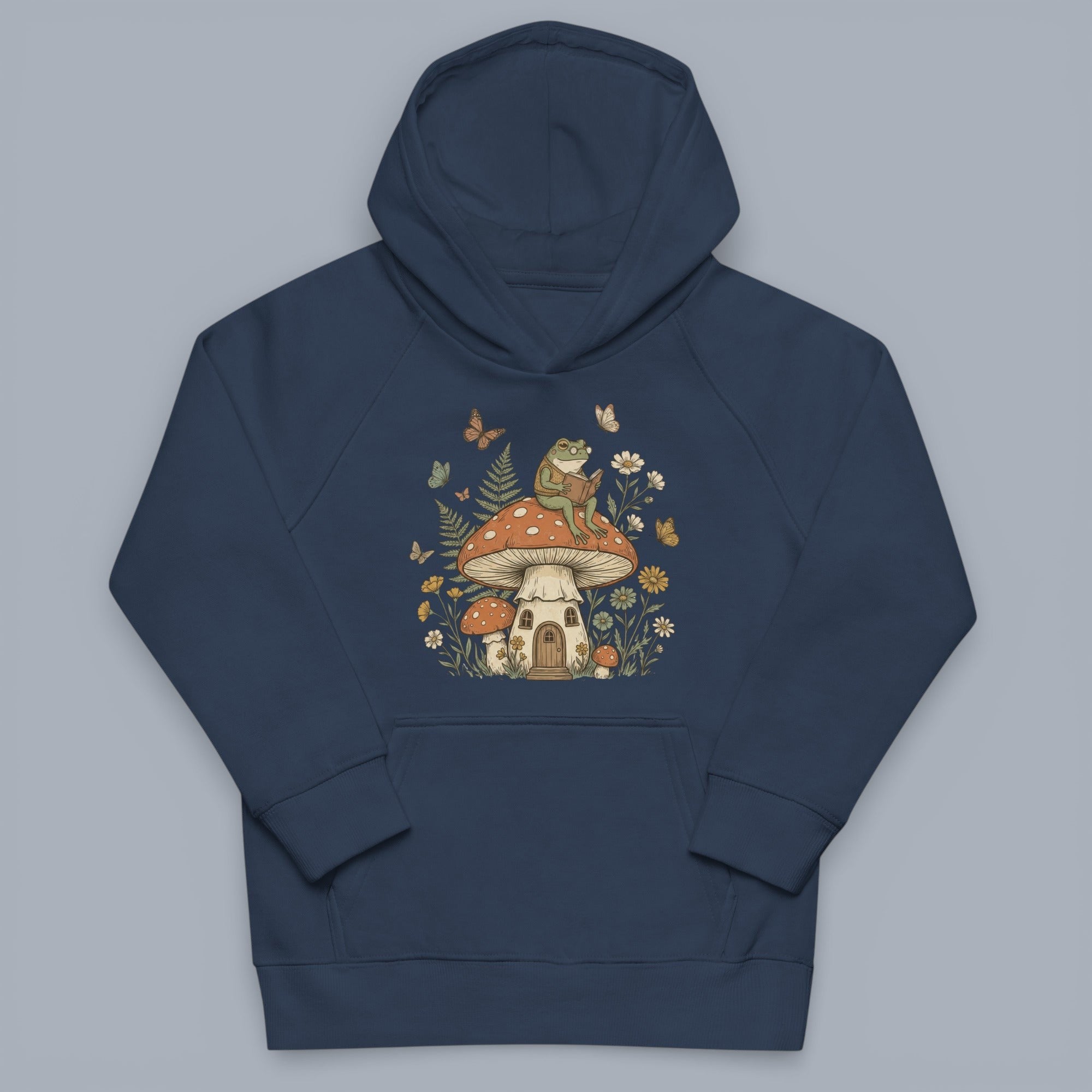 Coocosh hooded sweatshirt featuring a whimsical design of a frog reading a book atop a mushroom house, surrounded by flowers and butterflies, in navy blue, presented on a flat surface. A cozy, imaginative statement piece for everyday wear. The fabric appe