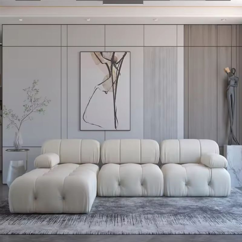 Coocosh modular sectional sofa in plush white fabric, featuring deep tufted cushions and a chaise lounge for ultimate relaxation, presented in a modern living room setting with abstract art. This spacious arrangement offers comfortable seating and a sophi