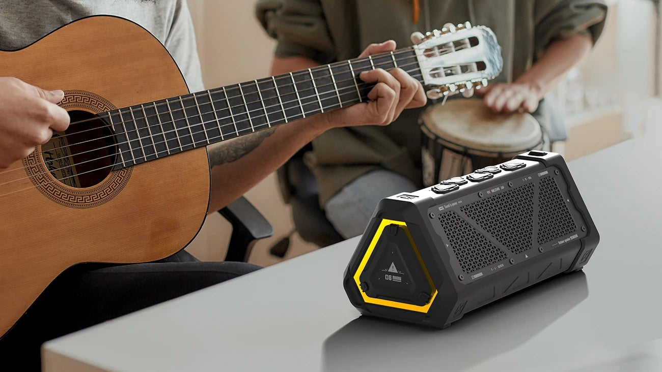 Two people playing music with a portable speaker on a table.
