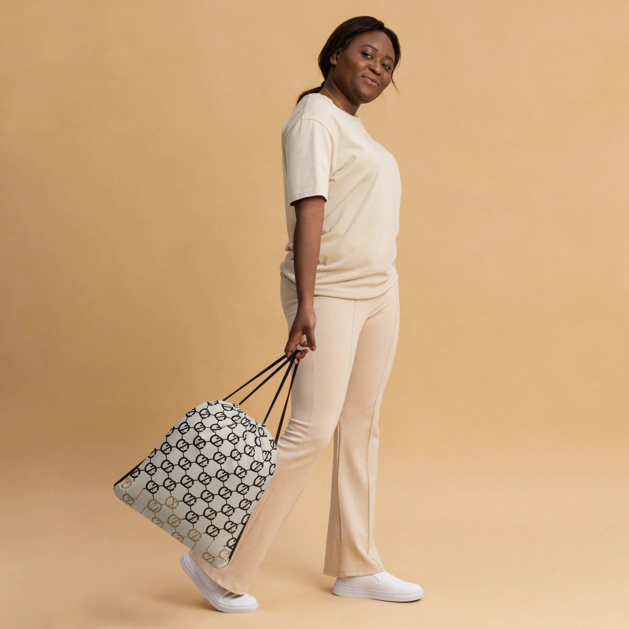 Coocosh Elite Cipher drawstring bag showcased by a model against a soft beige backdrop, combining stylish logo patterns with practical 30 lbs capacity and lightweight design, ideal for gym excursions or daily errands while exuding effortless elegance.