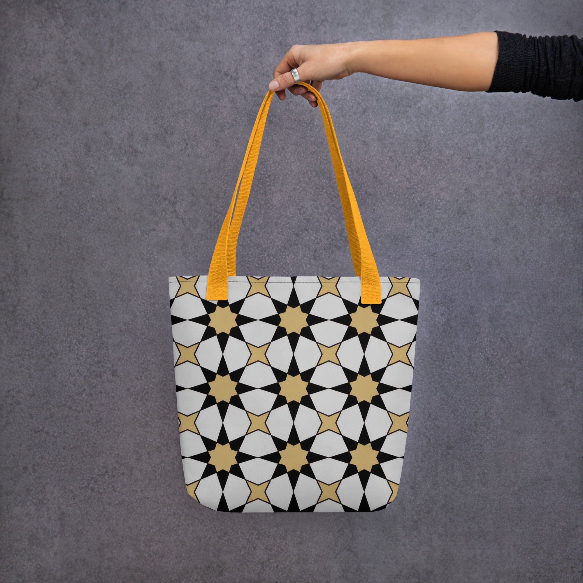 Coocosh Elysian Symmetry tote bag, adorned with a captivating floral and star design in black, white, and gold, featuring vibrant yellow straps, effortlessly elevates your everyday style while offering an elegant blend of artistry and functional versatility.