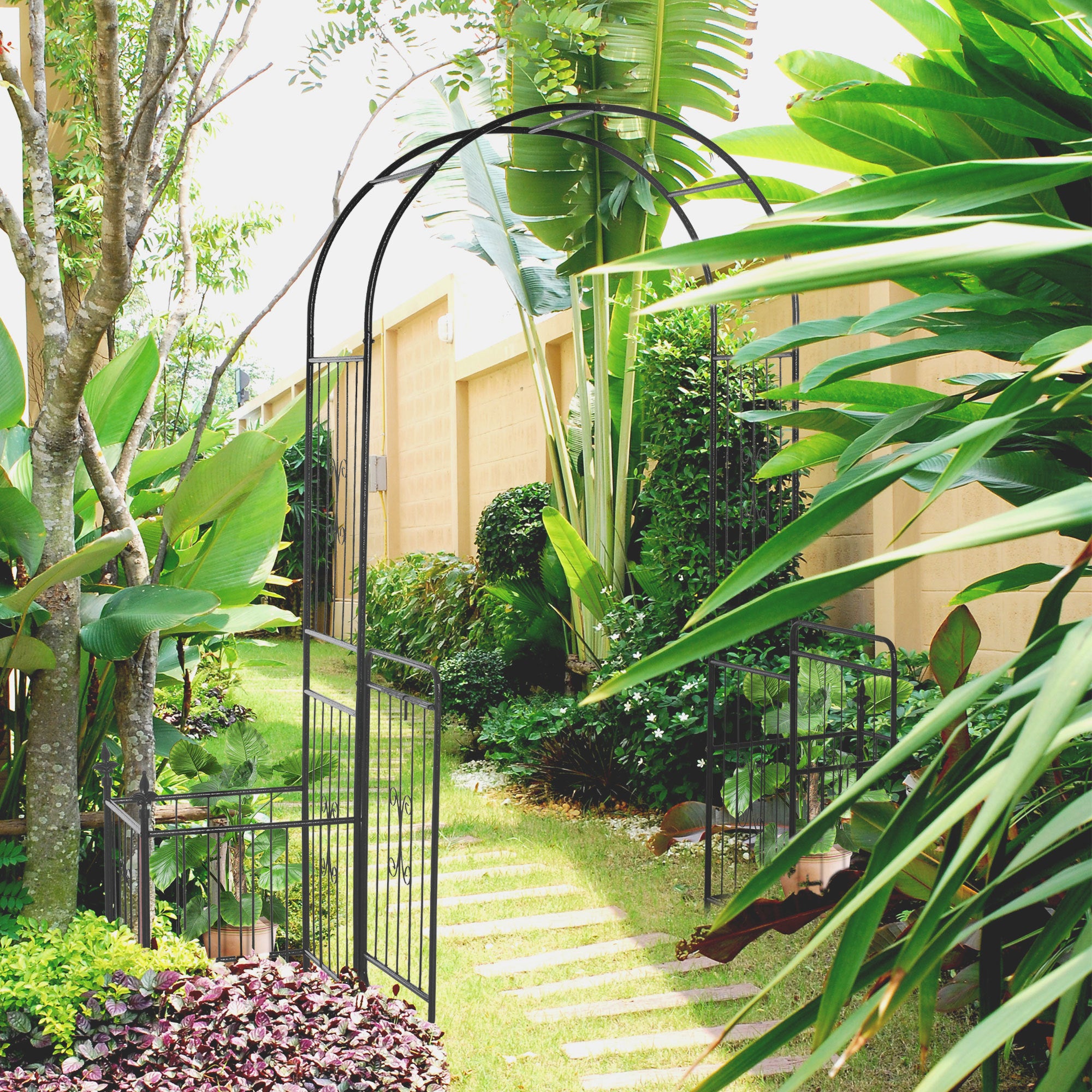 Coocosh Garden Gate in Elegant Black Metal with Intricate Design, Framed by Lush Green Foliage and Vibrant Plants, Creating a Tranquil Pathway, 6ft Height for Charming Outdoor Entry.
