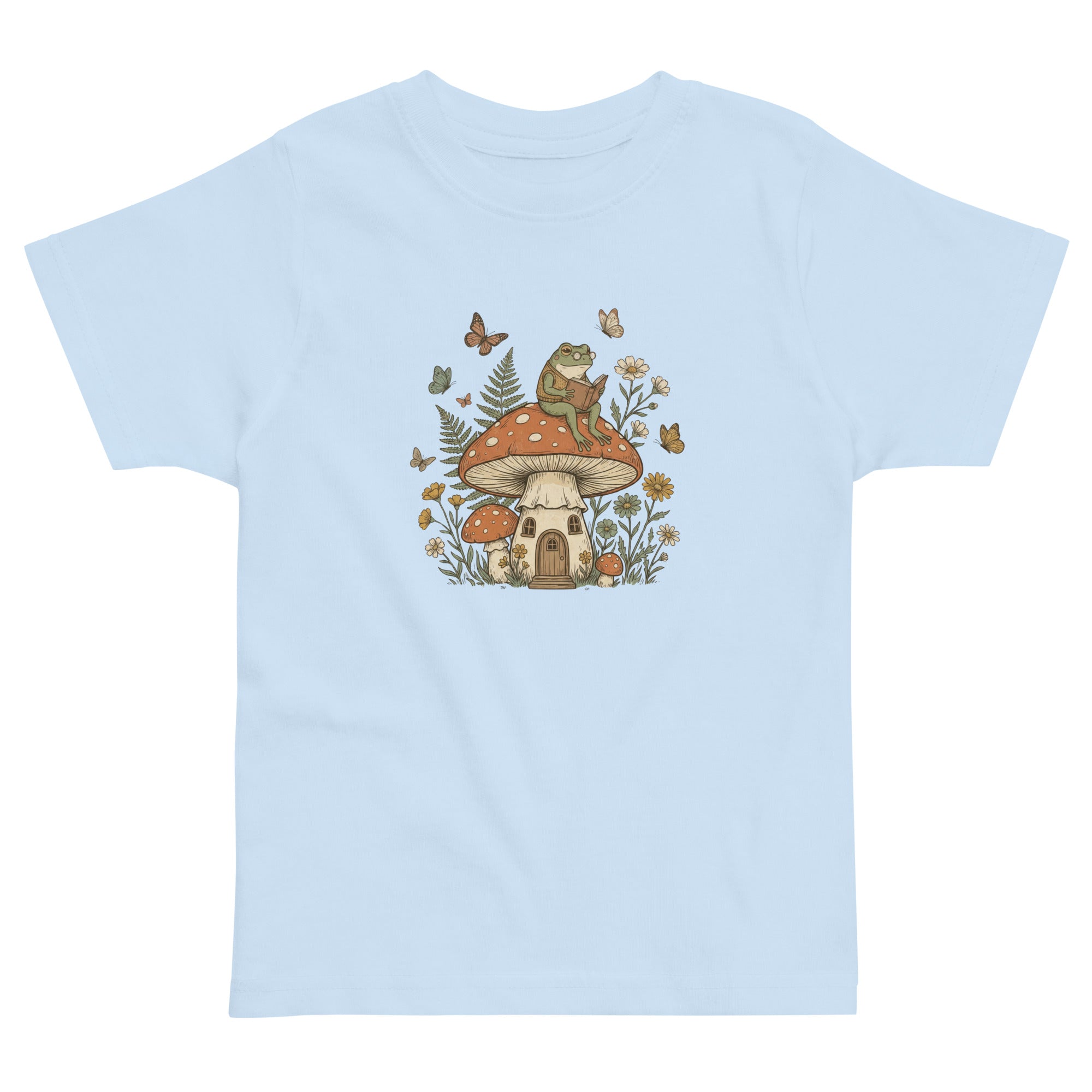 Coocosh t-shirt featuring a whimsical frog reading on a mushroom house, surrounded by butterflies. Soft blue color and comfortable fit for children. A magical scene printed.